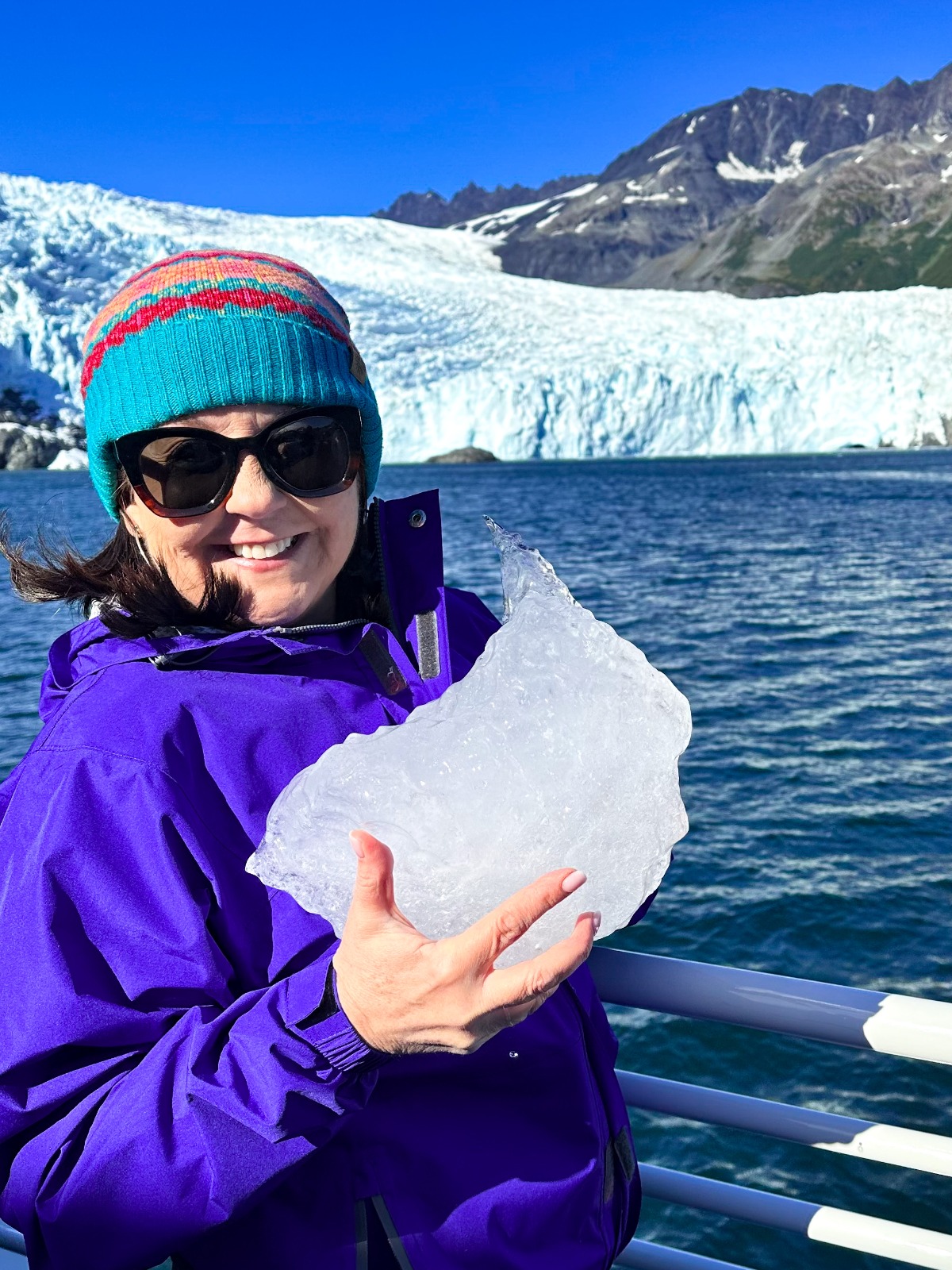 Charlee holding a piece of glacier ice in front of an Alaskan tidewater glacier